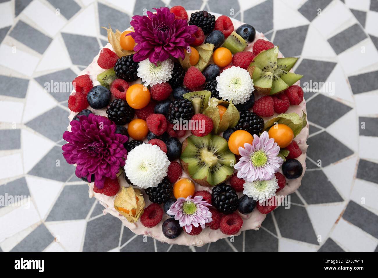 Un gâteau décoré de fruits et de fleurs. Banque D'Images