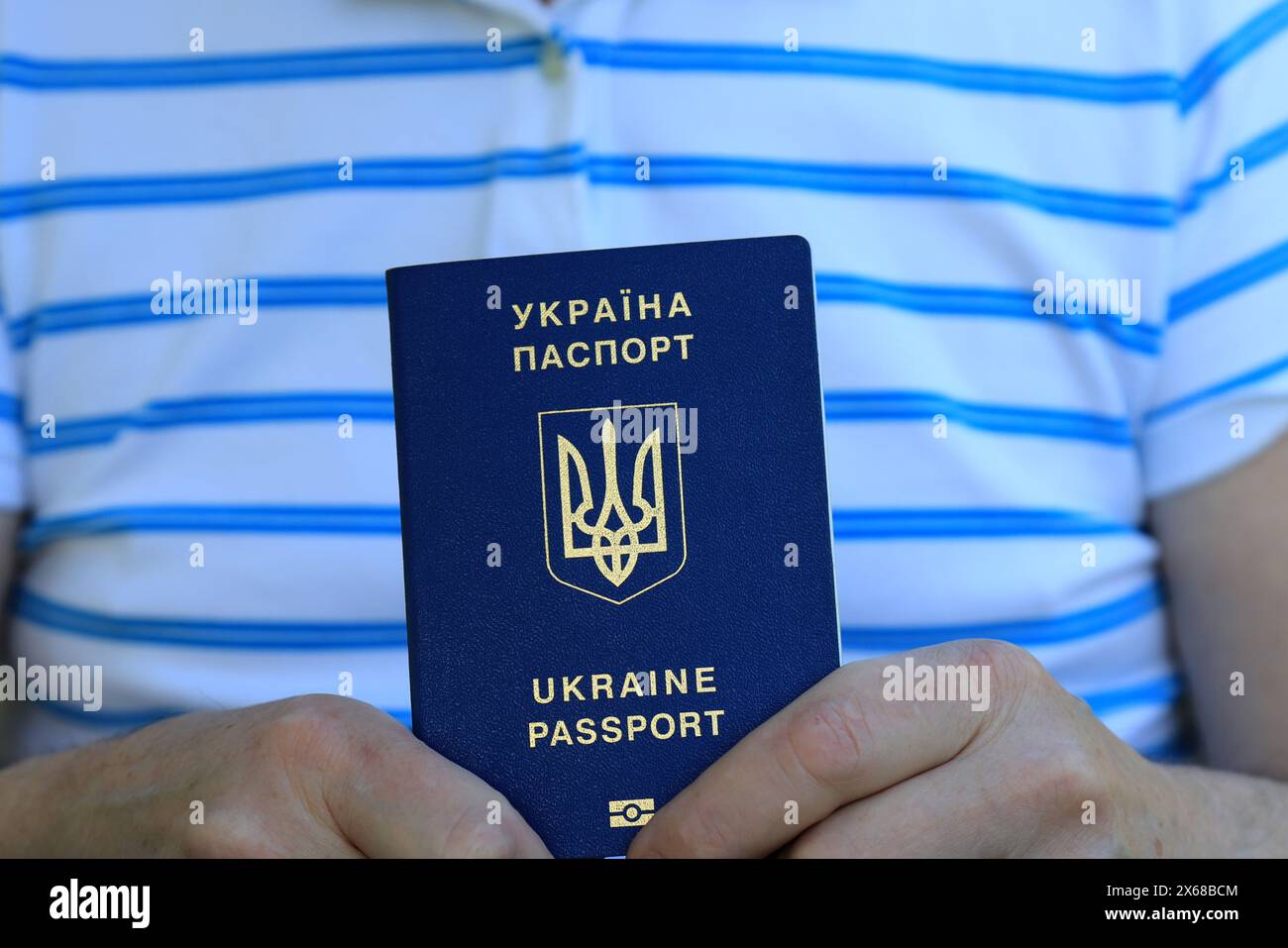 Un homme tient dans ses mains un passeport ukrainien avec une inscription en ukrainien - passeport de l'Ukraine. Concept de voyage, réfugié, touriste, émigrant, mobi Banque D'Images