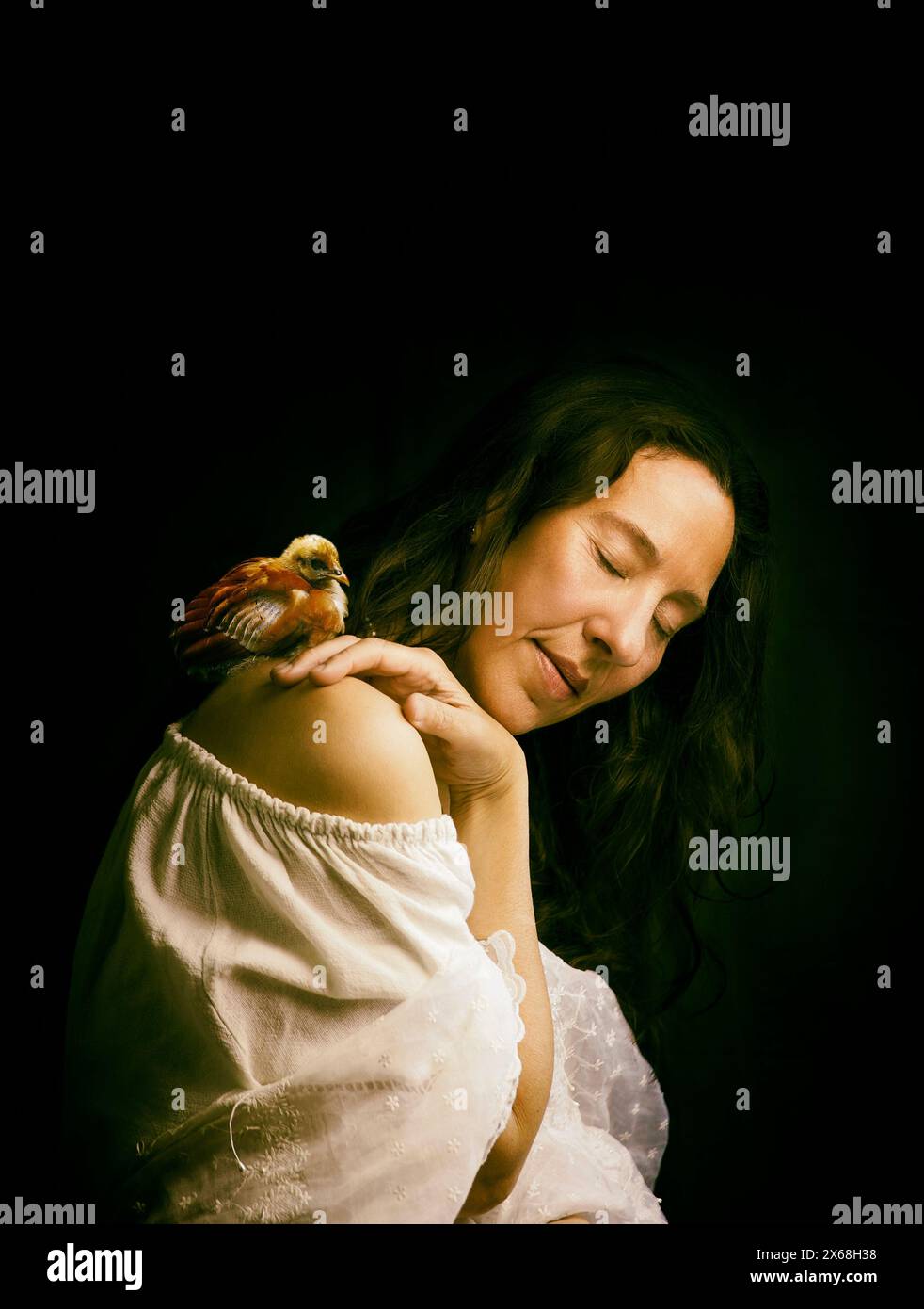 femme dans une attitude romantique avec un poussin sur son épaule, espagne Banque D'Images