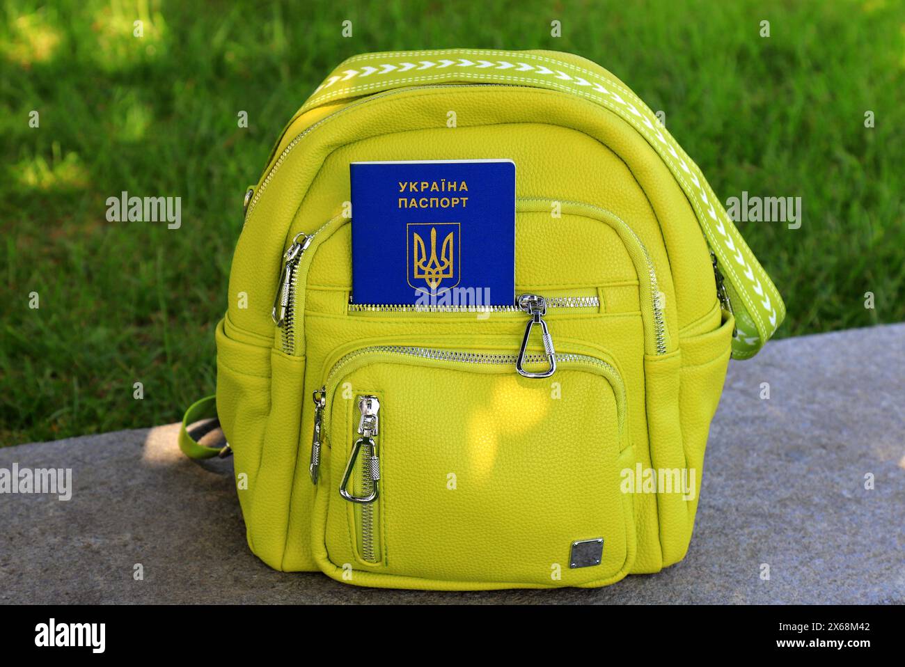 Un passeport de citoyen de l'Ukraine avec inscription en ukrainien - passeport de l'Ukraine se trouve dans le sac à dos vert. Concept de voyage, réfugié, tourisme, émigré Banque D'Images
