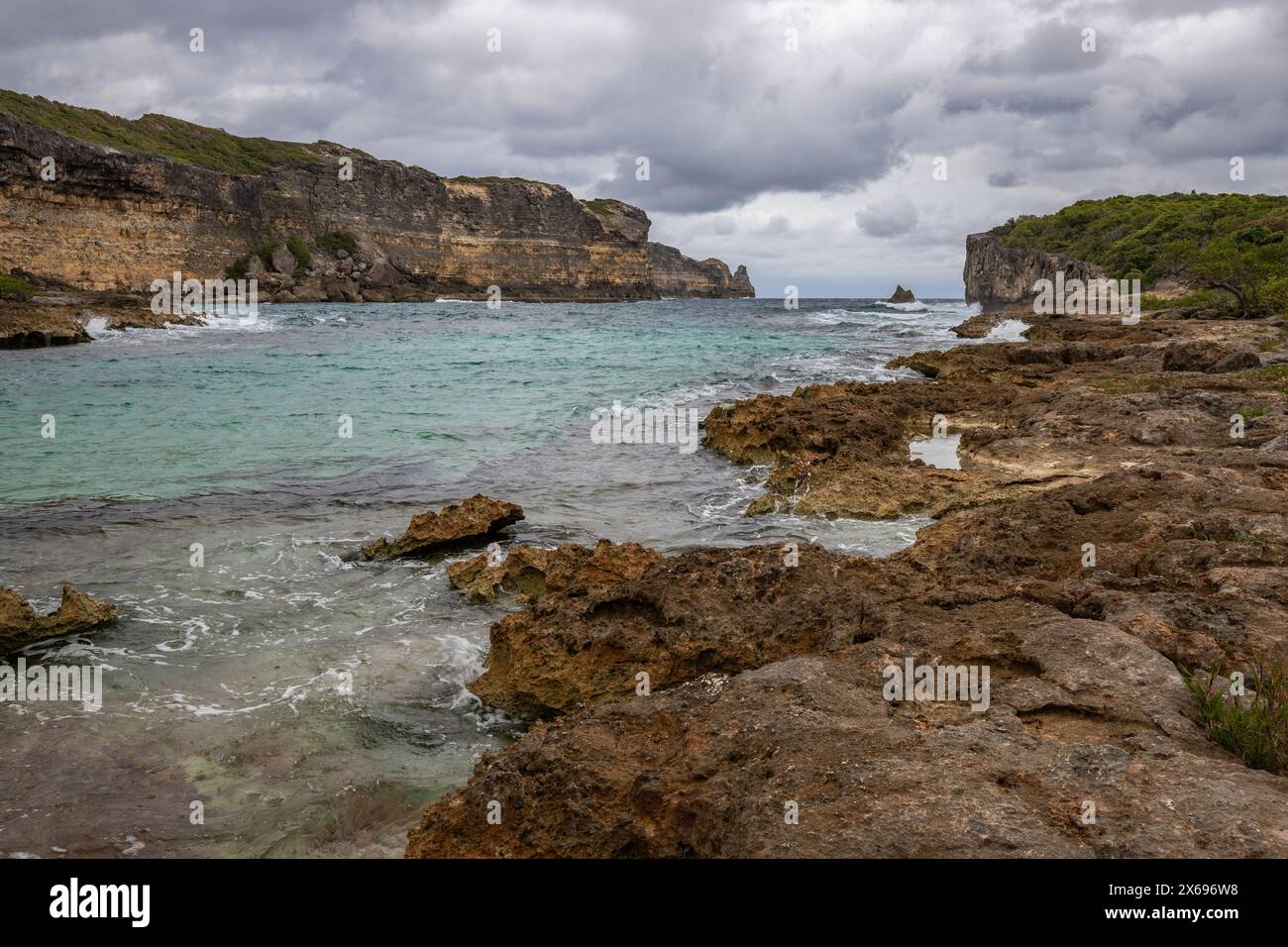 Côte rocheuse, longue baie au bord de la mer au coucher du soleil. Vue dangereuse sur la mer des Caraïbes. Climat tropical par jour nuageux à la porte d'Enfer, Grande Terre, Guadeloupe, Antilles françaises Banque D'Images