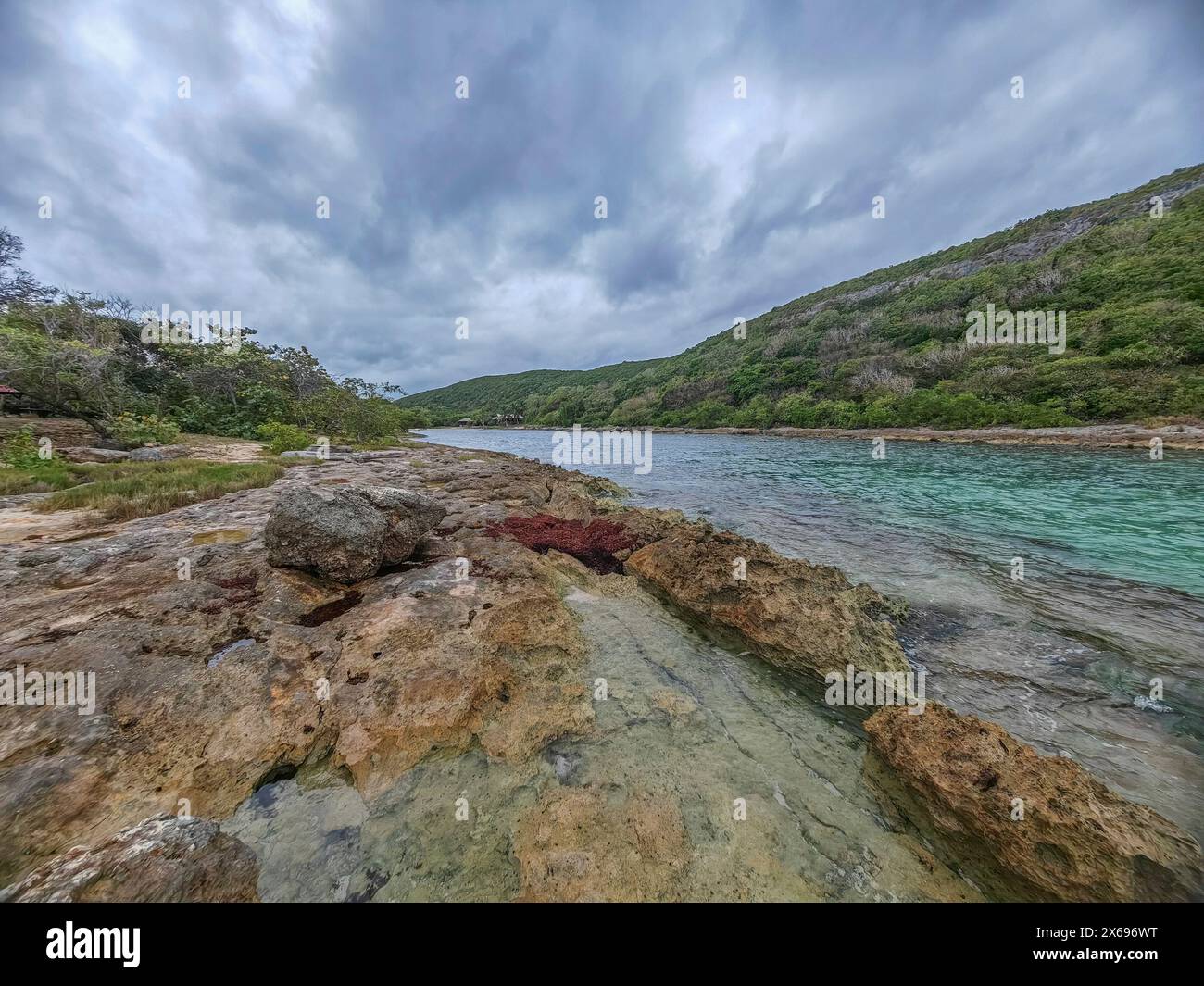 Côte rocheuse, longue baie au bord de la mer au coucher du soleil. Vue dangereuse sur la mer des Caraïbes. Climat tropical par jour nuageux à la porte d'Enfer, Grande Terre, Guadeloupe, Antilles françaises Banque D'Images