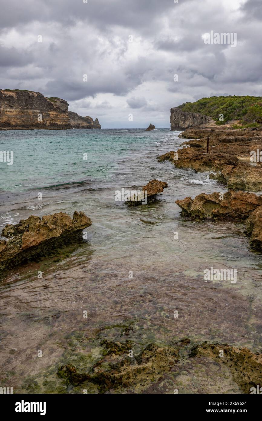 Côte rocheuse, longue baie au bord de la mer au coucher du soleil. Vue dangereuse sur la mer des Caraïbes. Climat tropical par jour nuageux à la porte d'Enfer, Grande Terre, Guadeloupe, Antilles françaises Banque D'Images
