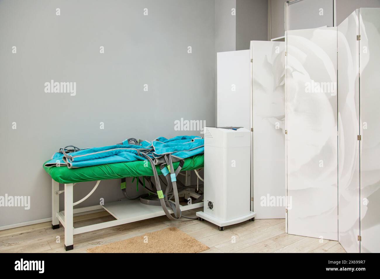 Détails intérieurs lumineux de la salle de massage moderne, table de massage verte avec costume de pressothérapie Banque D'Images