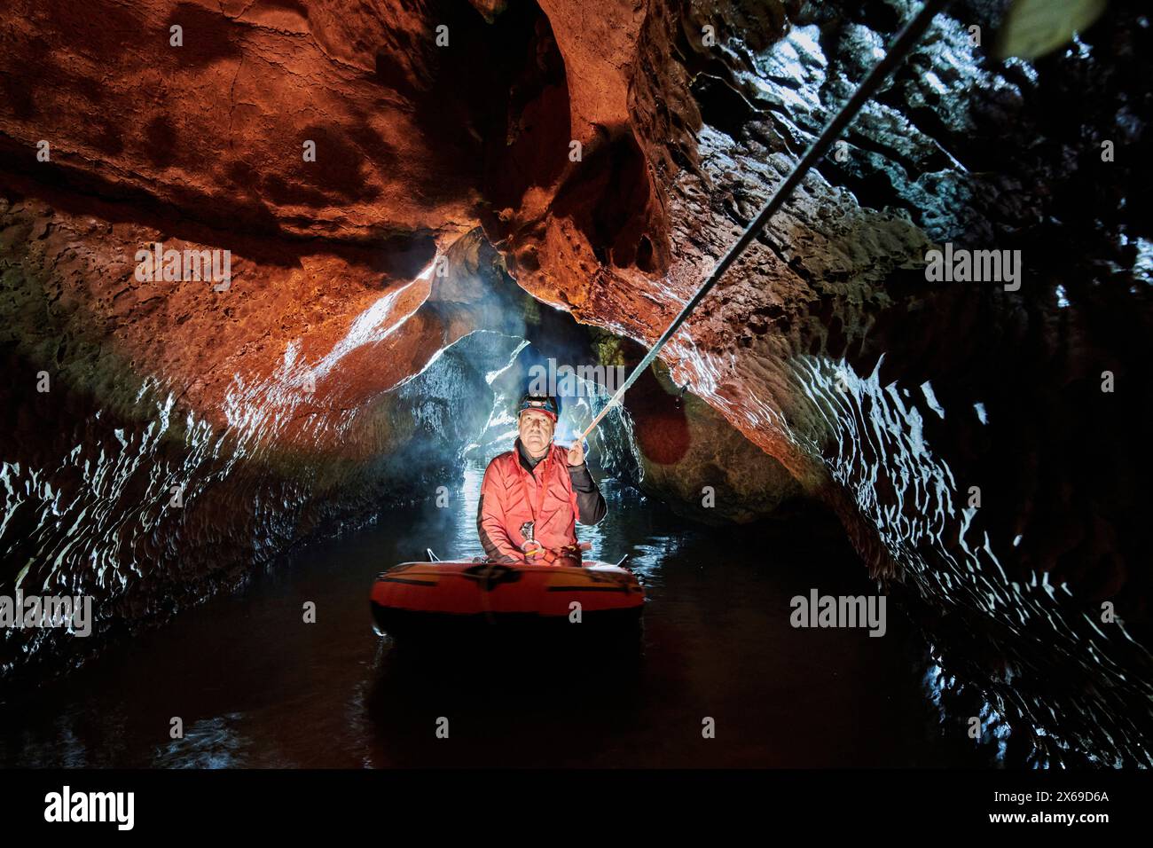 Spéléologue traverse un lac souterrain dans un canot en caoutchouc Banque D'Images