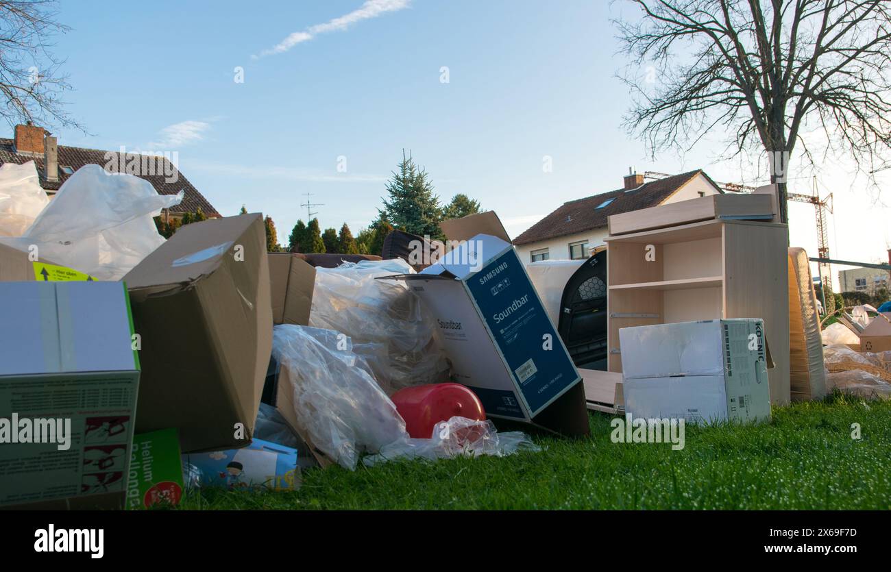 Beaucoup de déchets dans une ville près de la haus. Grandes ordures avec vieux meubles en bois, jouets, boîtes, sacs en plastique dans une rue et l'herbe verte au printemps ensoleillé tra Banque D'Images