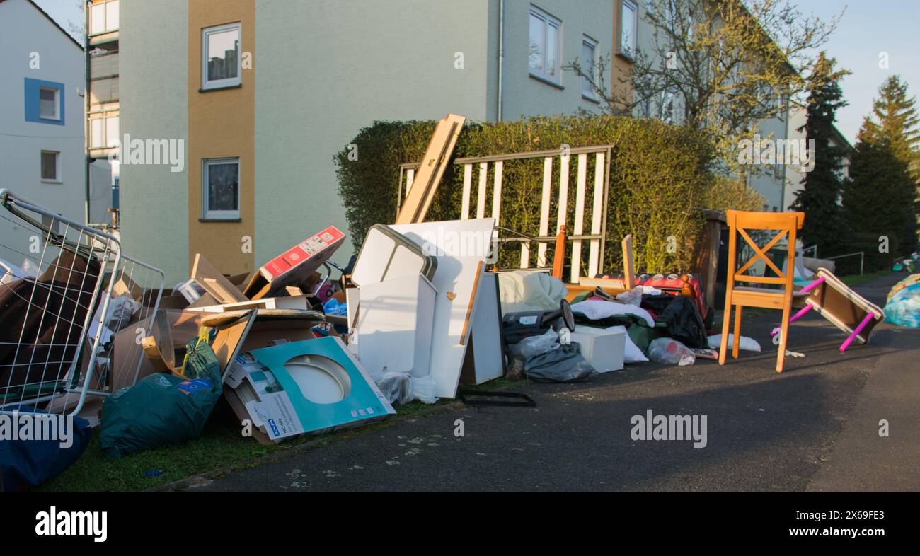 Déchets dans une ville près de la maison. Grandes ordures avec vieux meubles en bois, jouets, boîtes, sacs en plastique dans une rue et de l'herbe verte dans la décharge de déchets ensoleillée de printemps Banque D'Images