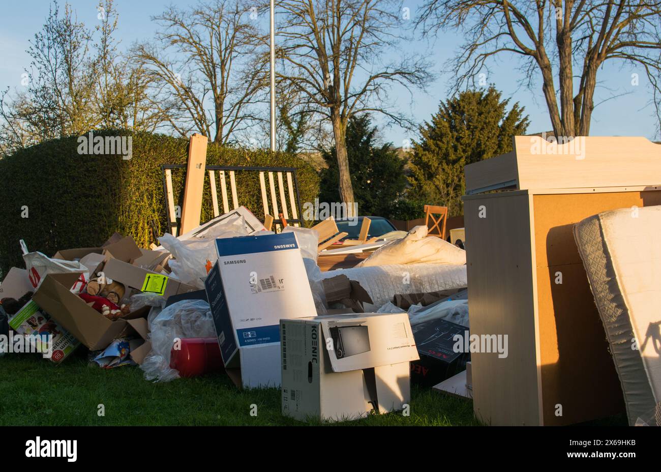 Grandes ordures avec vieux meubles en bois, jouets, boîtes, sacs en plastique dans une rue et herbe verte au printemps ensoleillé jour de décharge des ordures en Allemagne. Beaucoup de gaspillage moi Banque D'Images