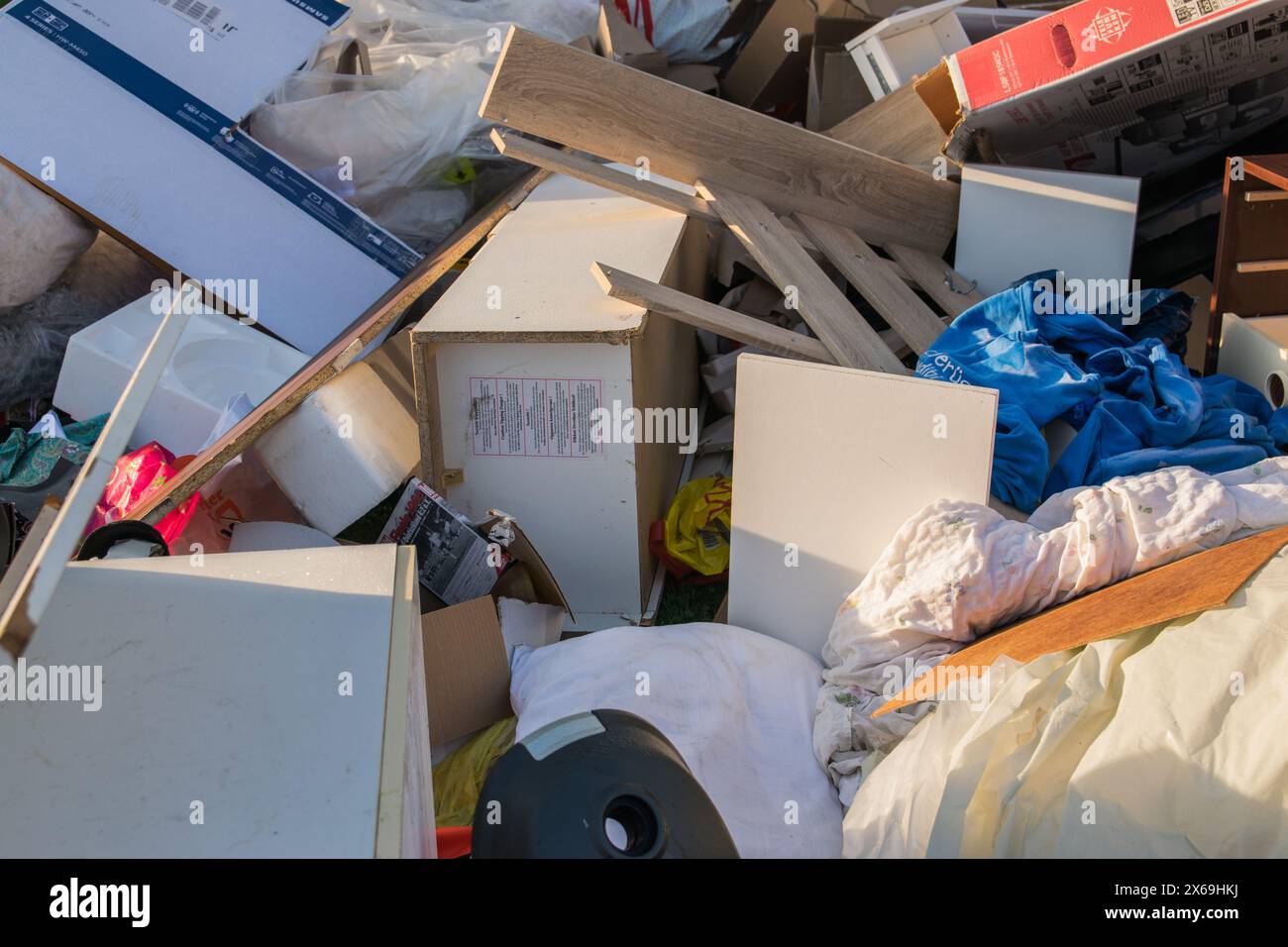 Grandes ordures avec vieux meubles en bois, jouets, boîtes, sacs en plastique dans une rue et herbe verte au printemps ensoleillé jour de décharge des ordures en Allemagne. Beaucoup de gaspillage moi Banque D'Images