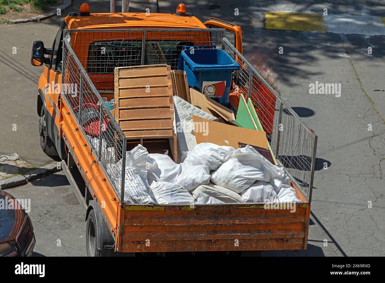 Camion de tup avec dos ouvert et tas de déchets ramassés dans la rue Banque D'Images