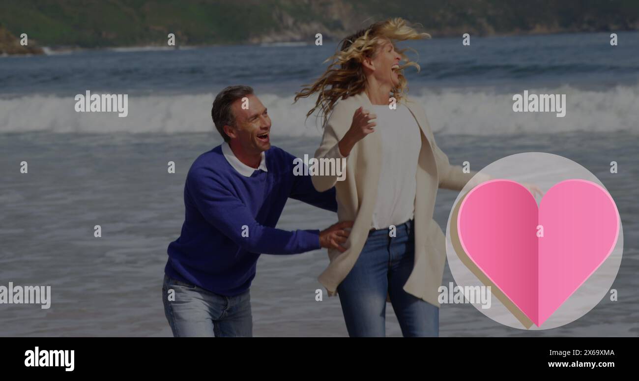 Image de l'icône de coeur sur un couple caucasien dans l'amour courir sur la plage Banque D'Images