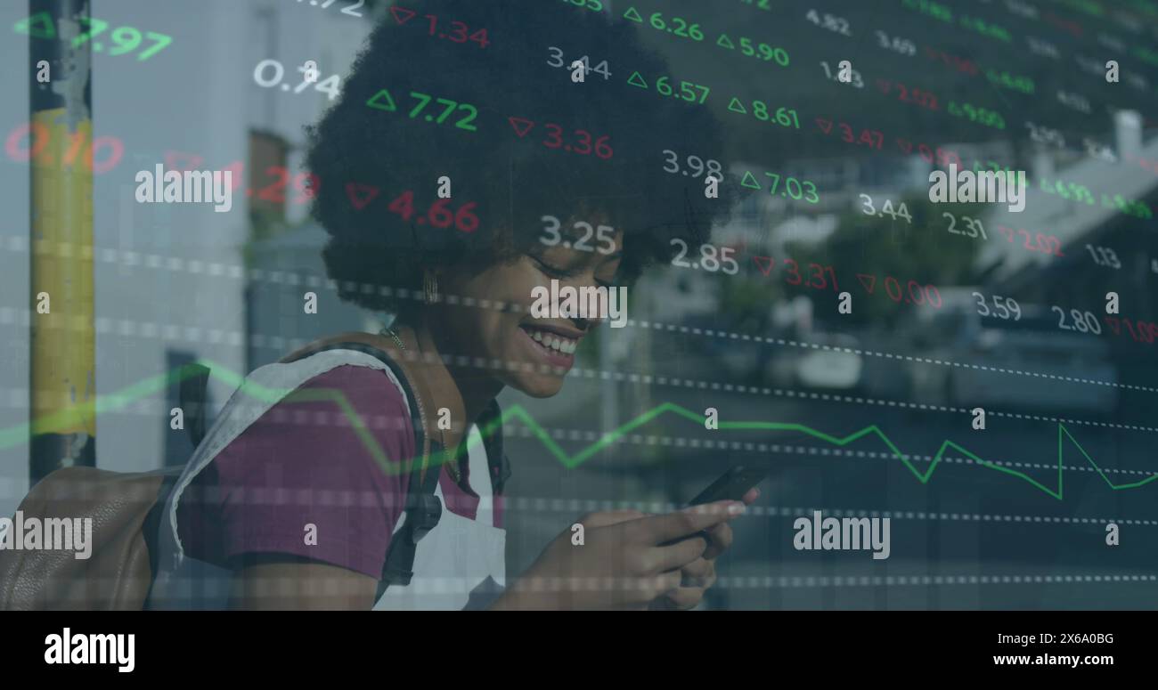 Image de la table de négociation sur une femme biraciale souriante discutant à l'aide d'un smartphone Banque D'Images