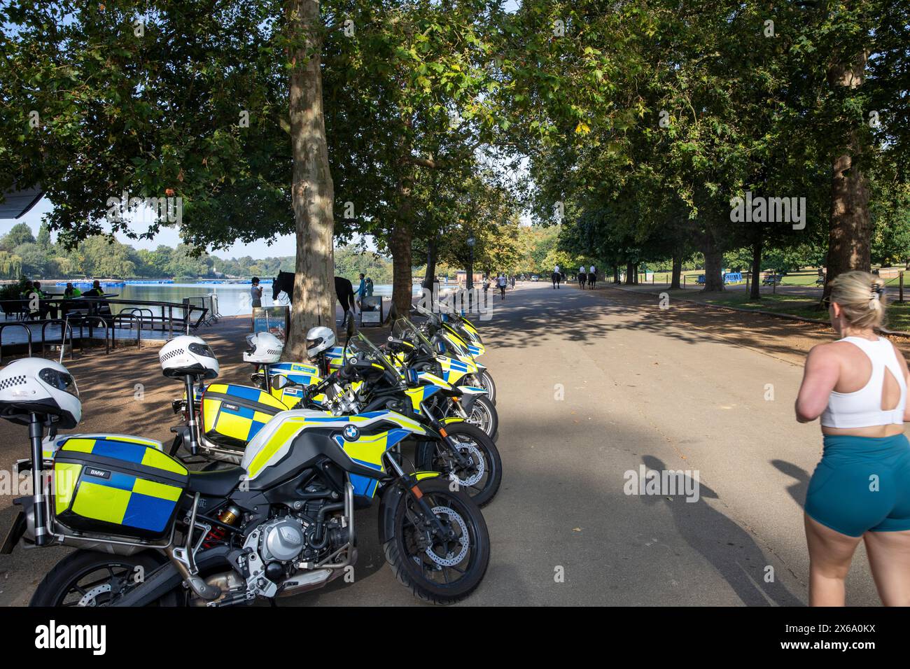 Hyde Park Londres, police métropolitaine motos motos garées devant le café au Serpentine alors que la femme blonde fait du jogging et court devant, Angleterre, Royaume-Uni, 2023 Banque D'Images