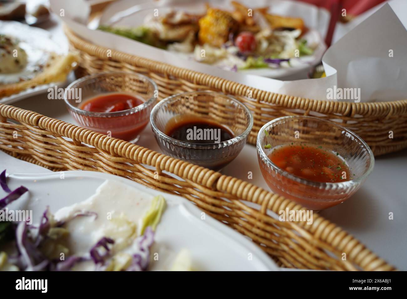 Nourriture du restaurant dans un panier en osier avec des sauces sur la table Banque D'Images