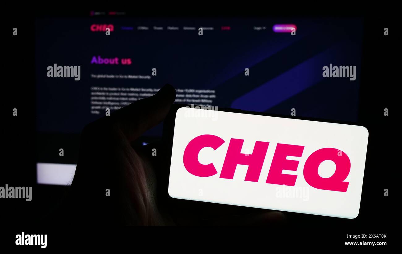 Personne tenant un smartphone avec le logo de la société américaine de cybersécurité CHEQ ai technologies Ltd en face du site Web. Concentrez-vous sur l'affichage du téléphone. Banque D'Images