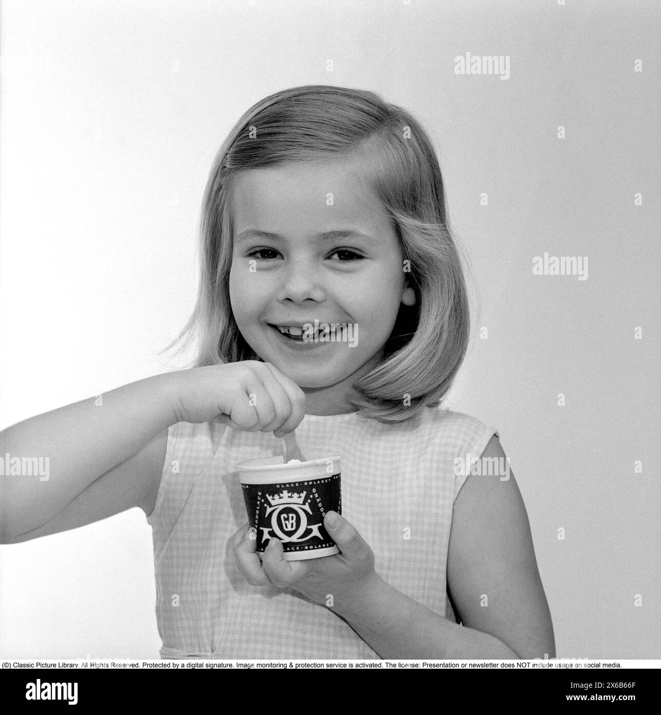 La crème glacée dans les années 1960 Une jeune fille mange de la crème glacée avec une cuillère dans une tasse en papier. 1961 Kristoffersson réf CS97-4 Banque D'Images
