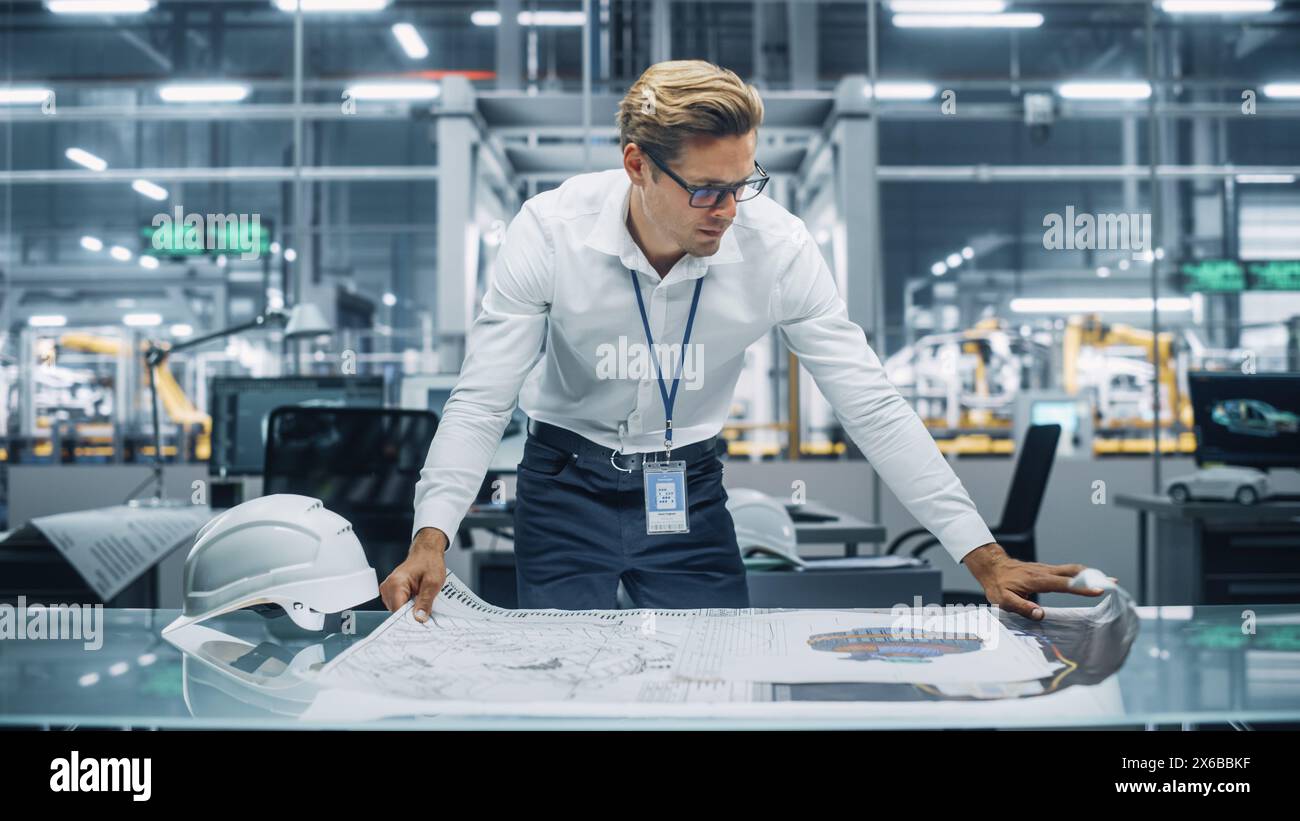 Ingénieur professionnel en chemise blanche regardant un plan technique au travail dans un bureau à l'usine d'assemblage de voitures. Spécialiste industriel travaillant sur les pièces de véhicules dans l'installation de développement technologique. Banque D'Images