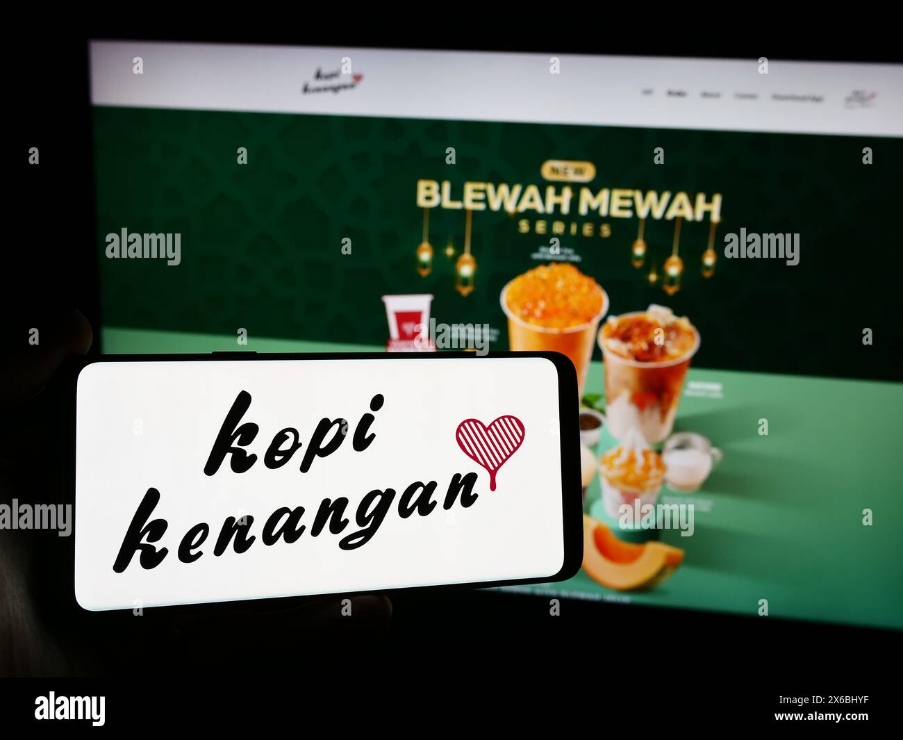 Personne tenant un smartphone avec le logo de la société de chaîne de café indonésienne Kopi Kenangan en face du site Web. Concentrez-vous sur l'affichage du téléphone. Banque D'Images