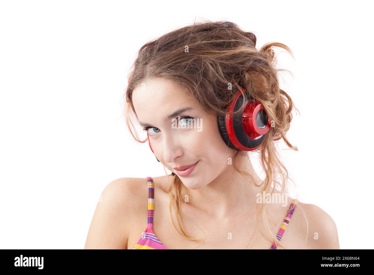 Portrait d'une jeune femme souriante qui écoute de la musique à travers des écouteurs rouges, regarde dans la caméra avec ses yeux bleus, tout en étant isolée sur un Banque D'Images