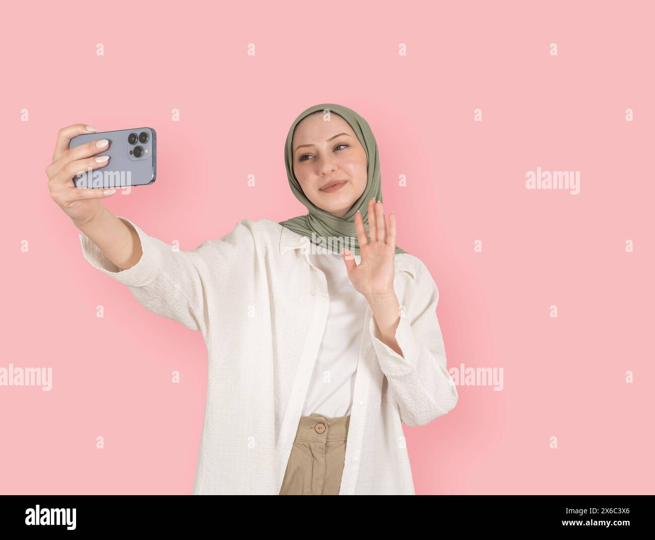 portrait de jeune amical amusant positif caucasien fille musulmane en hijab prenant selfie. Tenir le téléphone portable, parler appel vidéo, agiter la main, saluer. Banque D'Images