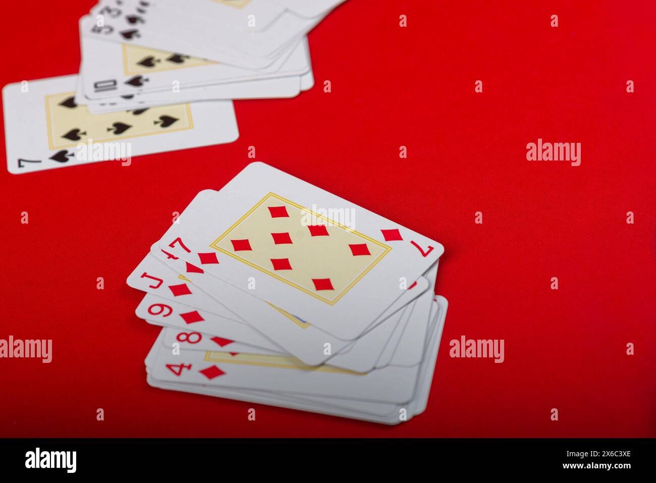 Diverses cartes à jouer disposées sur le plateau. Isolé sur fond rouge. Banque D'Images
