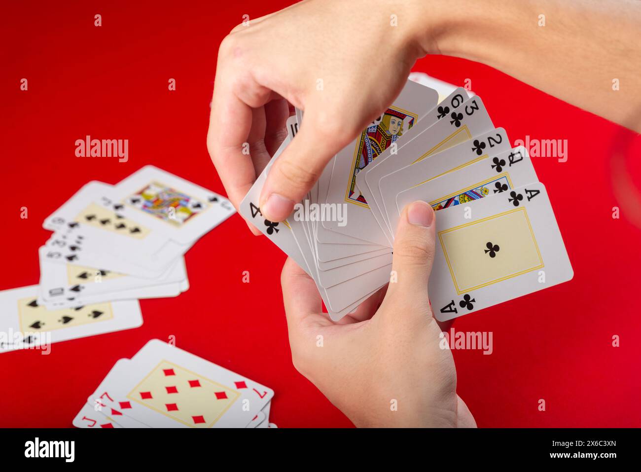Jeu de plateau. Cartes à jouer. cartes de poker dans une main de jeune homme. Isolé sur fond rouge. Banque D'Images