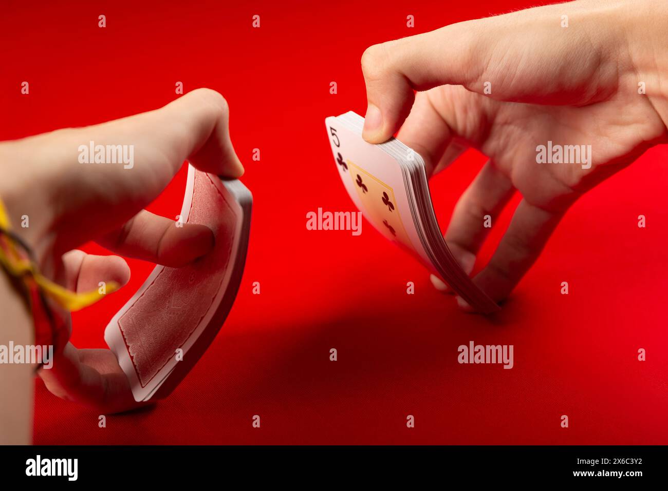 Main masculine mélangeant les cartes à jouer sur la table. Jeu de plateau. Isolé sur fond rouge. Banque D'Images