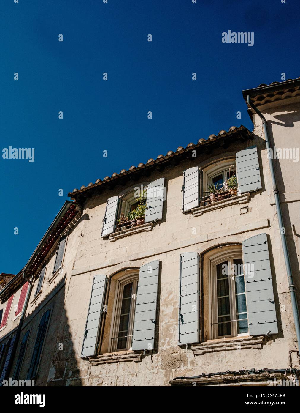Ancien bâtiment français avec volets bleus sous un ciel dégagé Banque D'Images