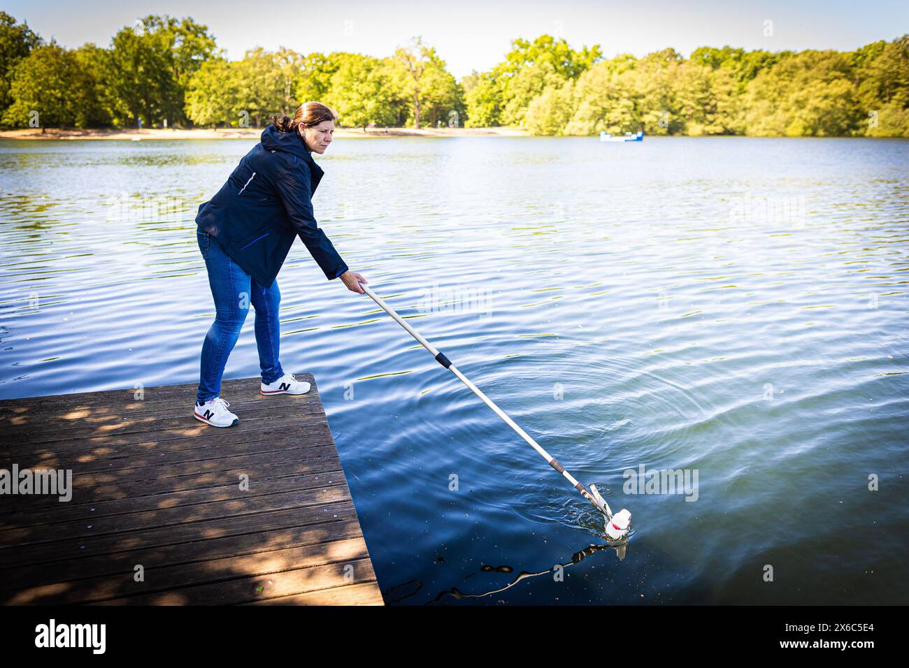 Langenhagen, Allemagne. 14 mai 2024. Nicole Siegismund, inspectrice en hygiène pour la région de Hanovre, prélève un échantillon d’eau du lac Silbersee dans la région de Hanovre pour surveiller la qualité de l’eau. Selon les autorités, la qualité de l’eau de la plupart des lacs de baignade surveillés en basse-Saxe est excellente au début de la saison balnéaire. Crédit : Moritz Frankenberg/dpa/Alamy Live News Banque D'Images