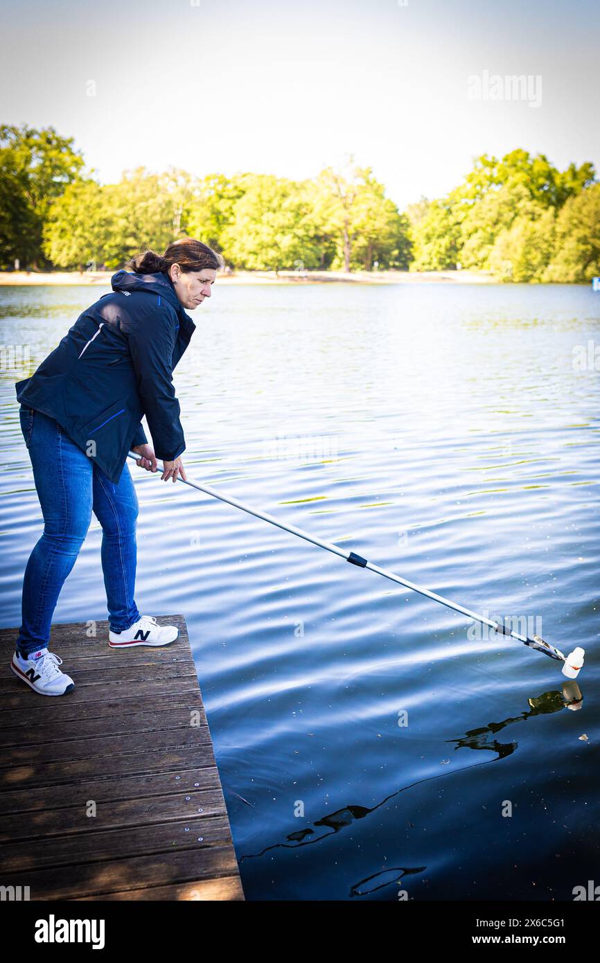 Langenhagen, Allemagne. 14 mai 2024. Nicole Siegismund, inspectrice en hygiène pour la région de Hanovre, prélève un échantillon d’eau du lac Silbersee dans la région de Hanovre pour surveiller la qualité de l’eau. Selon les autorités, la qualité de l’eau de la plupart des lacs de baignade surveillés en basse-Saxe est excellente au début de la saison balnéaire. Crédit : Moritz Frankenberg/dpa/Alamy Live News Banque D'Images