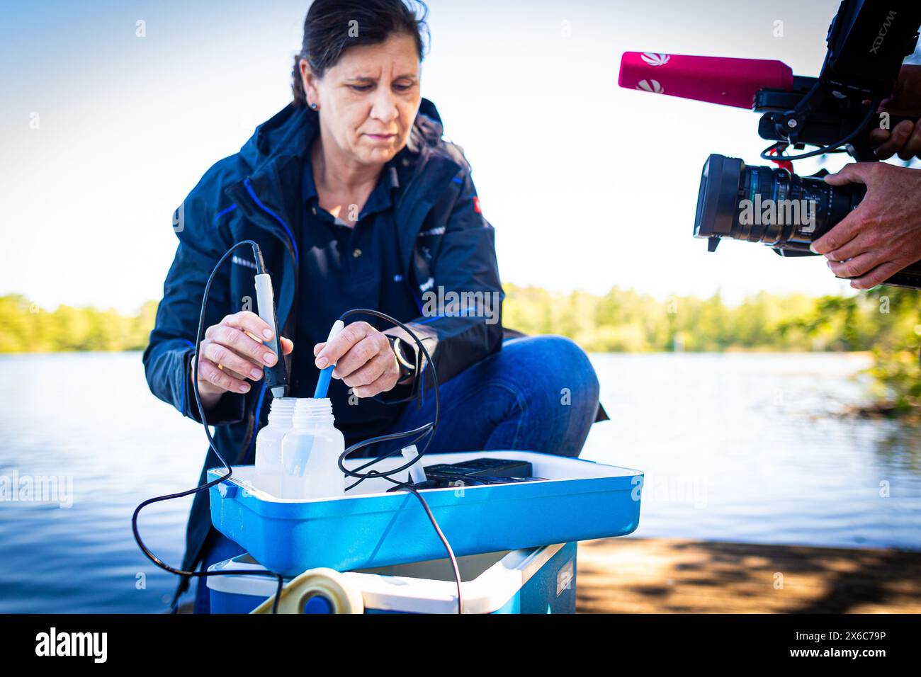 Langenhagen, Allemagne. 14 mai 2024. Nicole Siegismund, inspectrice en hygiène pour la région de Hanovre, examine un échantillon d'eau du lac Silbersee dans la région de Hanovre pour surveiller la qualité de l'eau. Selon les autorités, la qualité de l’eau de la plupart des lacs de baignade surveillés en basse-Saxe est excellente au début de la saison balnéaire. Crédit : Moritz Frankenberg/dpa/Alamy Live News Banque D'Images