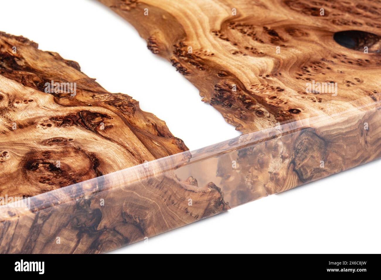 Plateau de table Live Edge en ronce d'orme avec rivière centrale en résine époxy sur fond blanc, combinant le bois naturel avec un matériau synthétique vue de près Banque D'Images