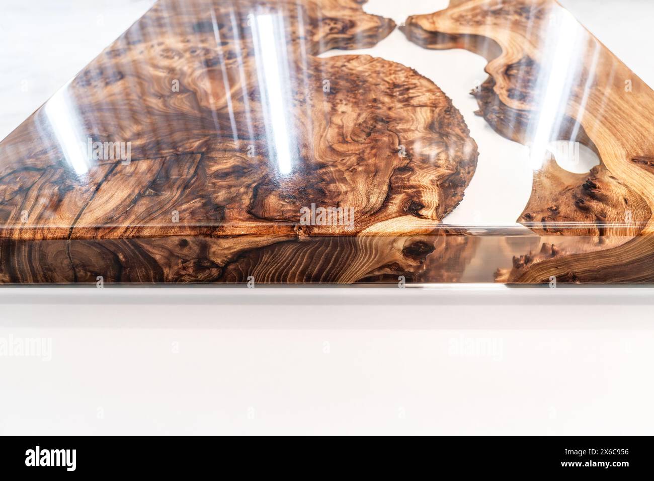 Plateau de table Live Edge en ronce d'orme avec rivière centrale en résine époxy sur fond blanc, combinant le bois naturel avec un matériau synthétique Banque D'Images
