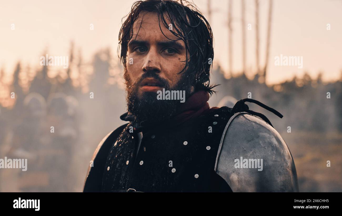 Beau roi chevalier médiéval sur le champ de bataille, regardant caméra. Portrait de Mighty Warrior Soldier contemplant la victoire. Guerre, invasion, conquête. Scène dramatique dans Cinematic Historic Reenactment Banque D'Images