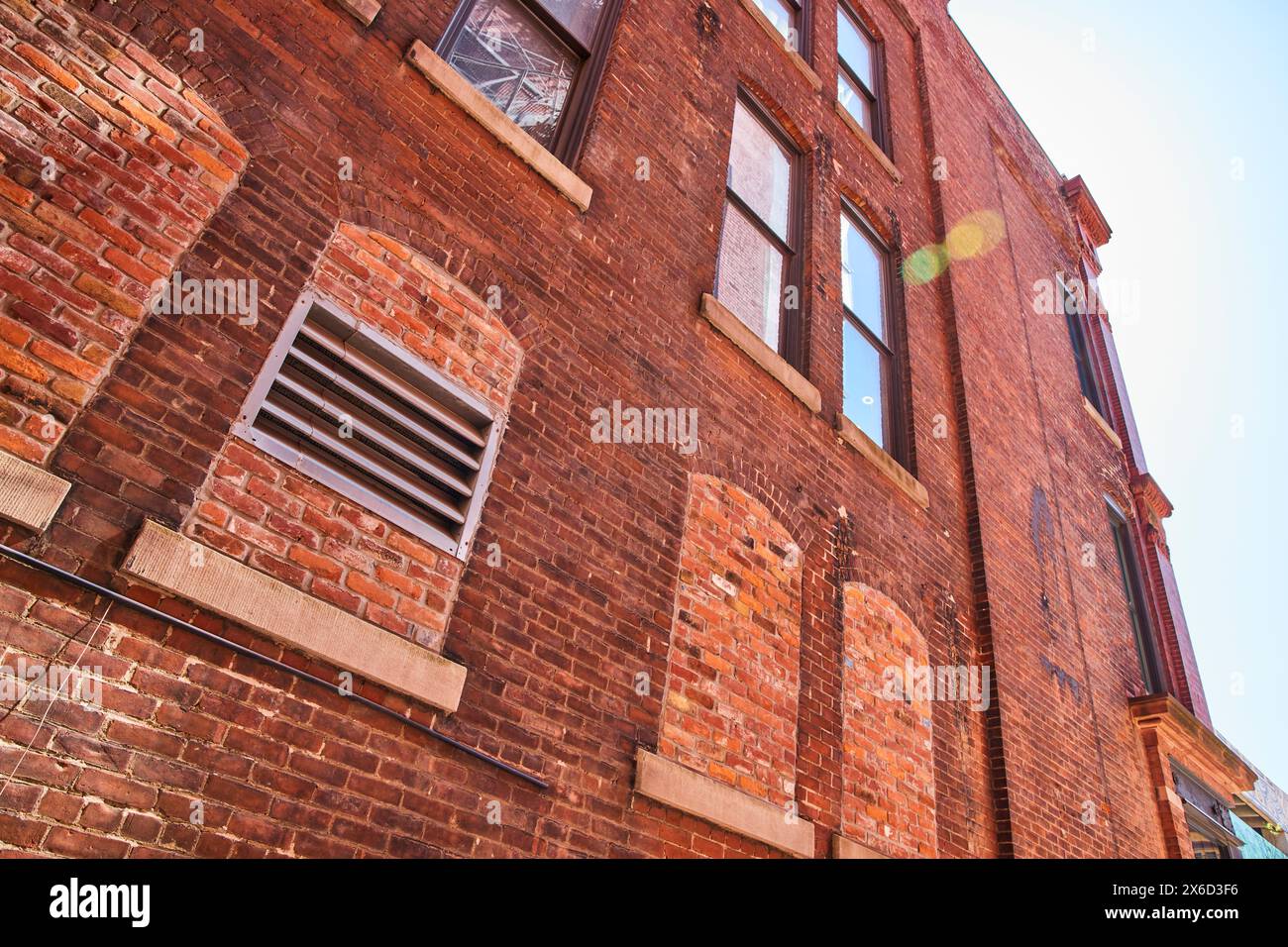 Façade en briques vintage ensoleillée avec fenêtres industrielles, vue à angle bas Banque D'Images