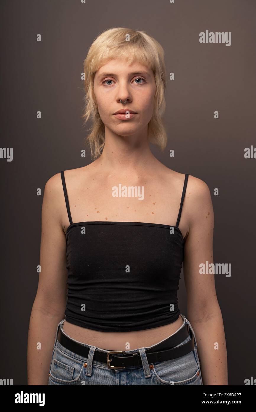 Portrait face à face d'une femme blonde dans un top noir et un Jean, photographie de studio mettant en valeur la mode et le style personnel, fond neutre. Banque D'Images