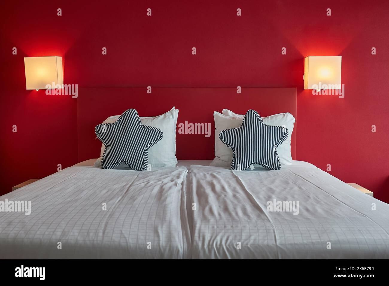 Lit d'hôtel avec draps blancs, mur rouge Banque D'Images