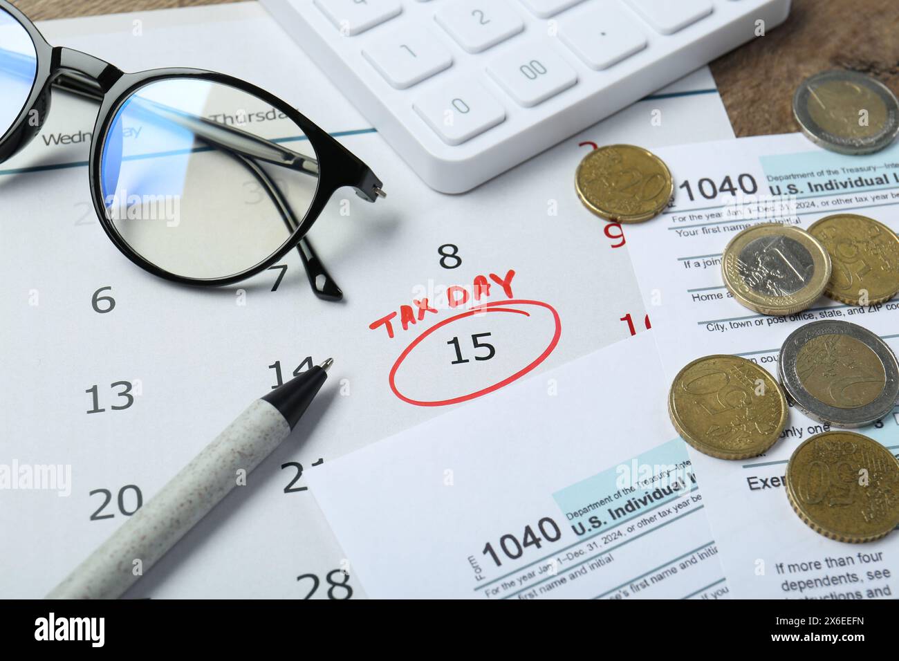 Calendrier avec rappel de date sur le jour de l'impôt, documents, stylo, pièces de monnaie, lunettes et calculatrice sur la table, gros plan Banque D'Images