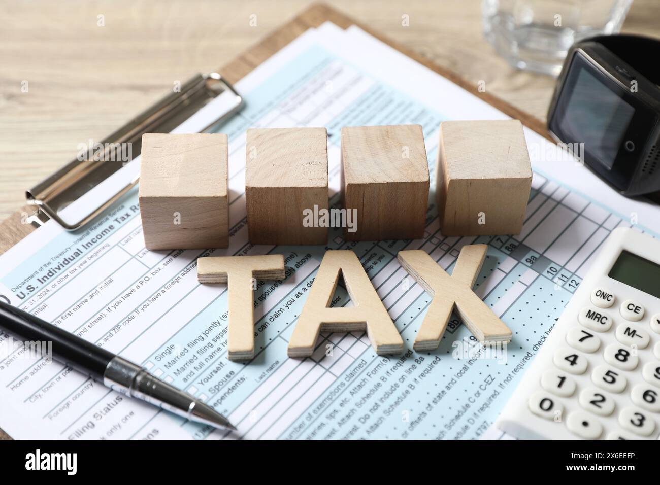 Word Tax, cubes, calculatrice, stylo et document sur table en bois, gros plan Banque D'Images