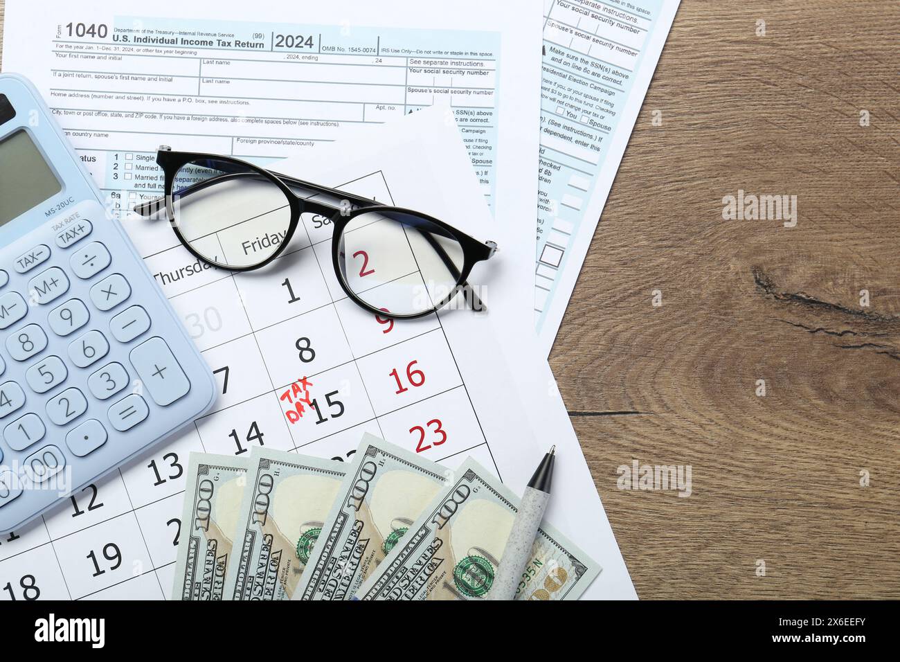 Calendrier avec rappel de date sur le jour des impôts, documents, argent, calculatrice et verres sur la table en bois, vue de dessus. Espace pour le texte Banque D'Images