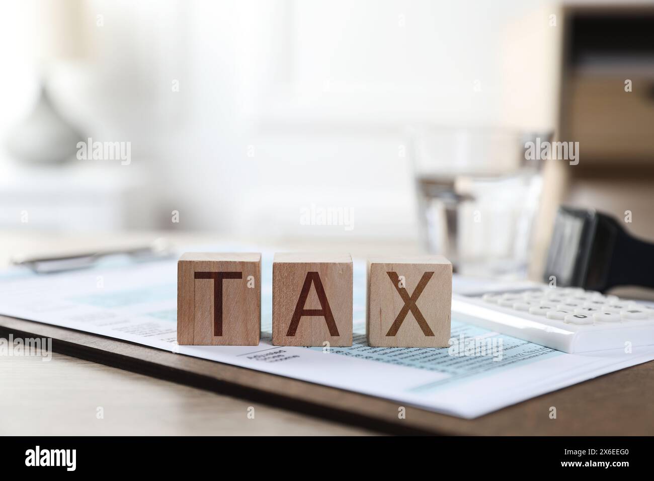 Cubes en bois avec le mot taxe et document sur la table, gros plan Banque D'Images