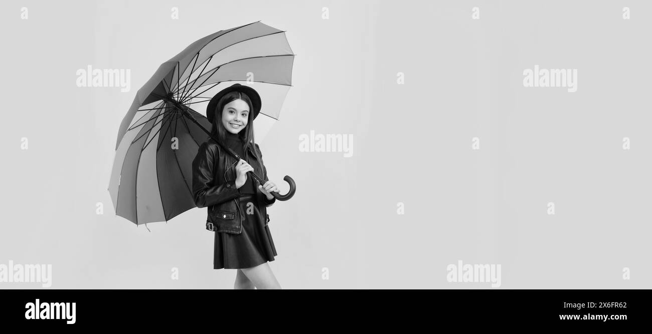 bonne jeune fille en chapeau et vêtements en cuir sous parapluie arc-en-ciel, temps d'automne. Enfant avec parapluie d'automne, temps pluvieux, affiche horizontale Banque D'Images