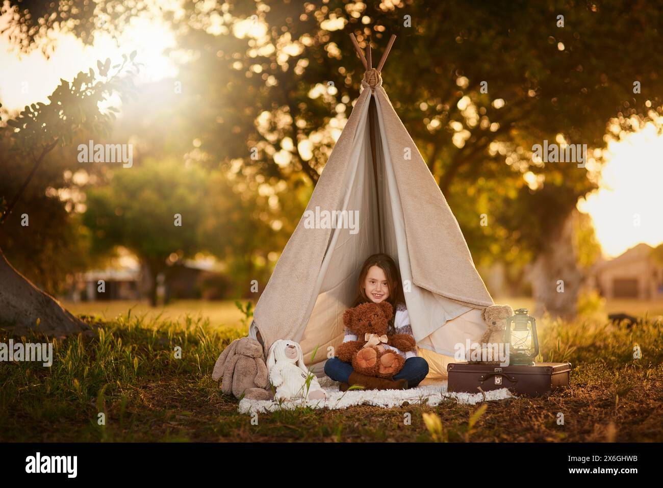 Tipi, tente et fille avec jouet dans le jardin dans la nature pour le plaisir, le jeu et le camping pour l'aventure ou l'imagination. Tissu, abri ou maison de fantaisie pour Banque D'Images