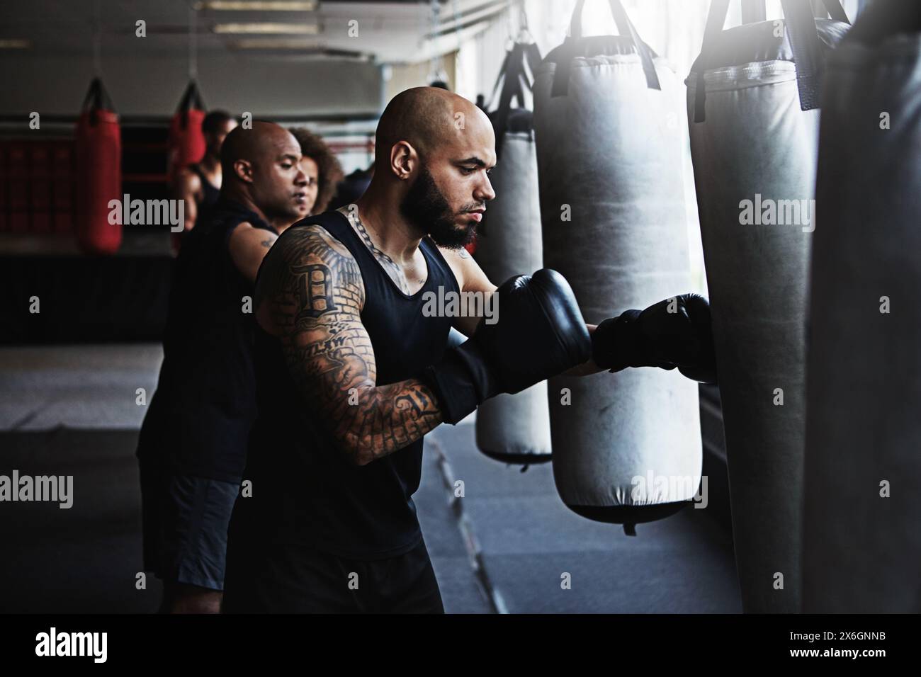 Hit, sac de punching et homme en classe de boxe pour entraînement, défi ou entraînement de compétition. Puissance, muscle et champion boxer dans l'exercice avec confiance Banque D'Images