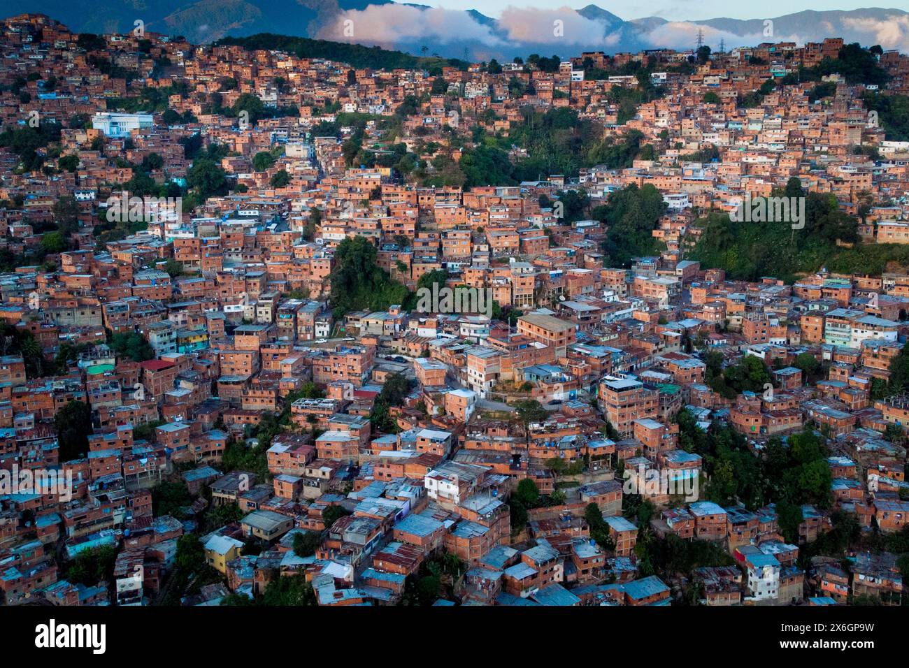 Vue aérienne de Caracas au coucher du soleil avec le quartier Petare, le plus grand bidonville du Venezuela et d'amérique latine, avec la montagne Avila dans l'arrière-pays Banque D'Images