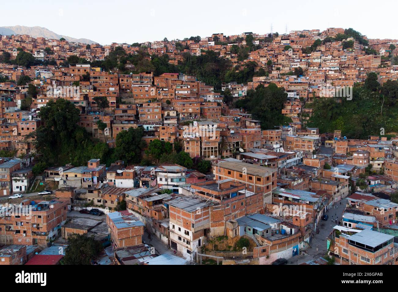 Vue aérienne de Caracas au coucher du soleil avec le quartier Petare, le plus grand bidonville du Venezuela et d'amérique latine, avec la montagne Avila dans l'arrière-pays Banque D'Images