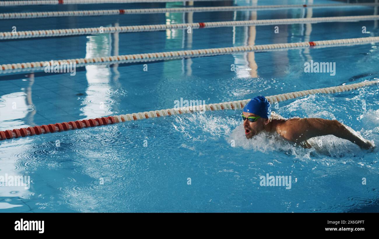 Course de nageurs masculins réussie, natation dans la piscine olympique. Athlète professionnel déterminé à remporter le championnat en utilisant le style papillon. Plan cinématographique haut en couleur. Banque D'Images