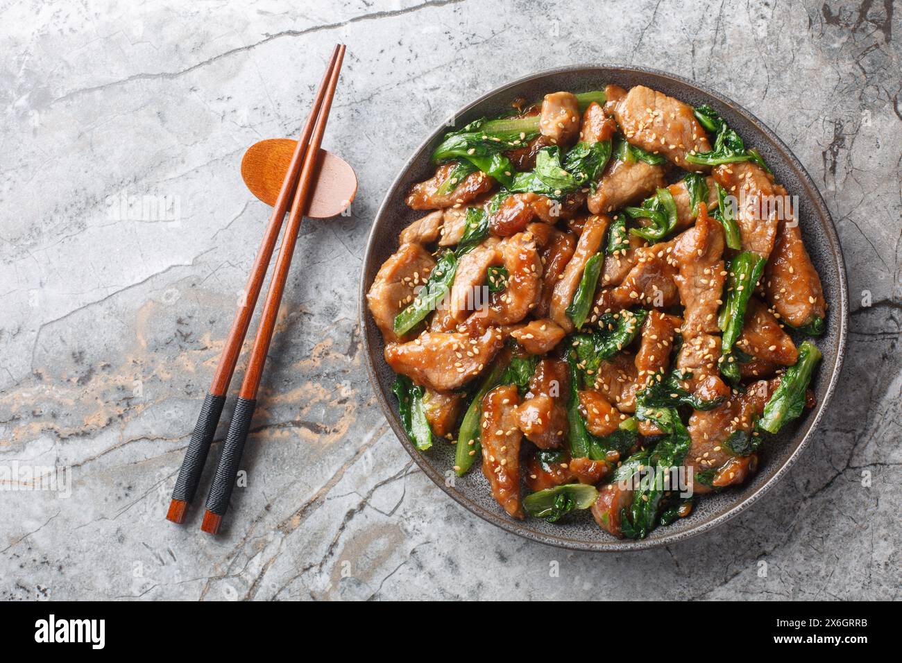 Filet de porc chinois sauté avec laitue romaine, sésame et ail dans une sauce soja gros plan dans une assiette sur la table. Vue horizontale de dessus f Banque D'Images