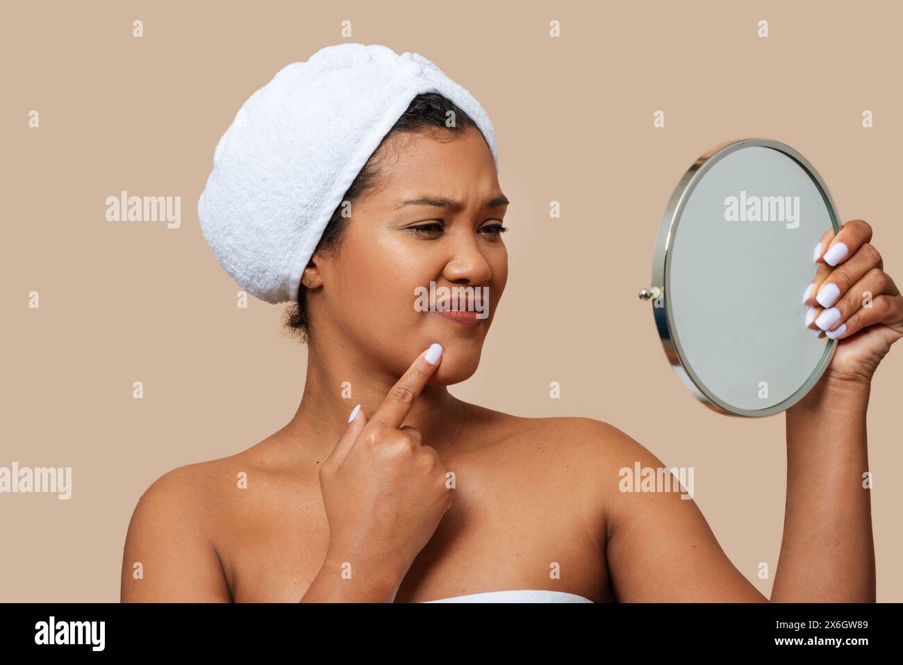 Femme examinant son visage en miroir, touchant Chin Banque D'Images