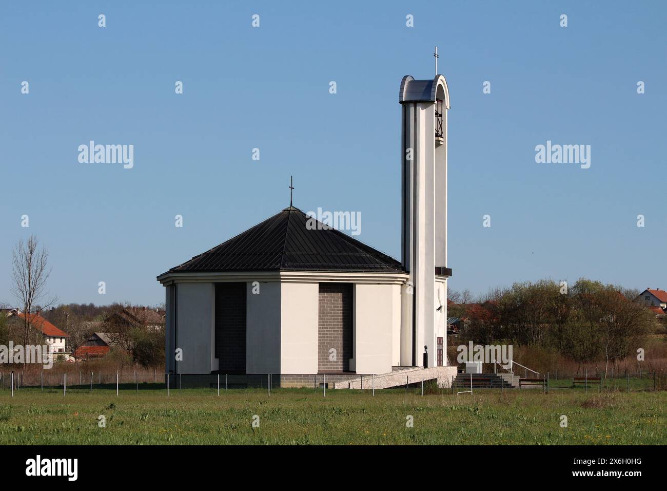 Nouvellement construit église catholique blanche et grise haut clocher avec croix de fer sur le dessus et grand mécanisme de sonnerie au milieu Banque D'Images